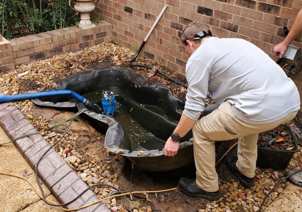 Person repairing a backyard pond.