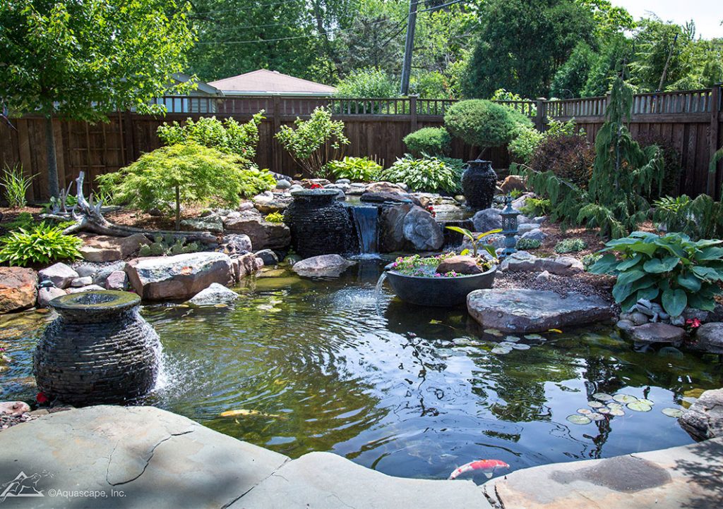 Garden pond with waterfall and lush greenery.