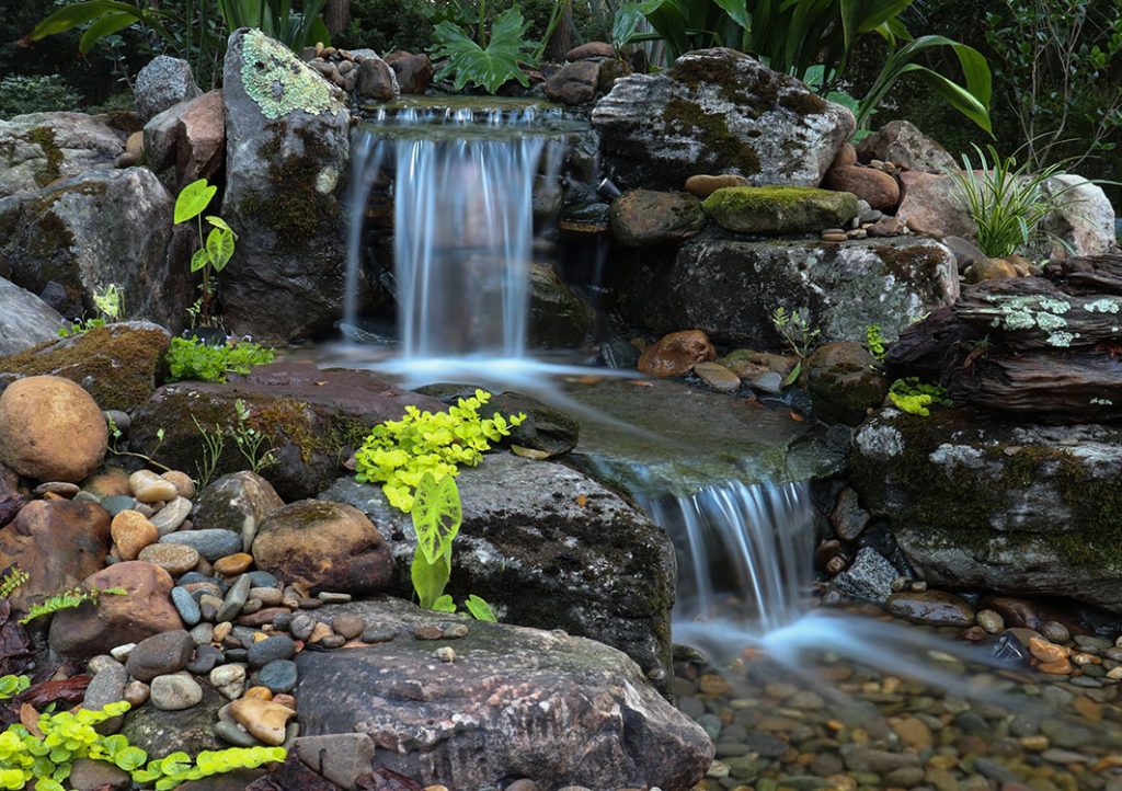 Small waterfall surrounded by rocks and greenery.