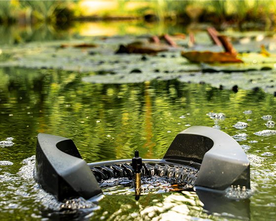 Robotic device floating in pond with lily pads.