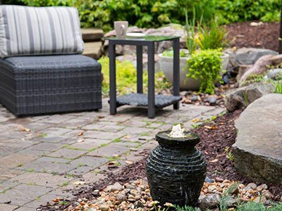 Cozy patio with chair and water fountain.