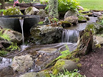 Serene garden pond with waterfall and rocks.