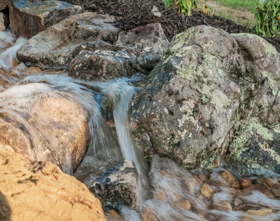 A water garden with a stream flowing over rocks.